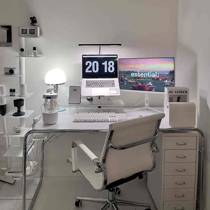 白を基調としたホームオフィス、デュアルモニターと整頓されたデスク、シンプルなオフィスチェアが配置された印象的な空間