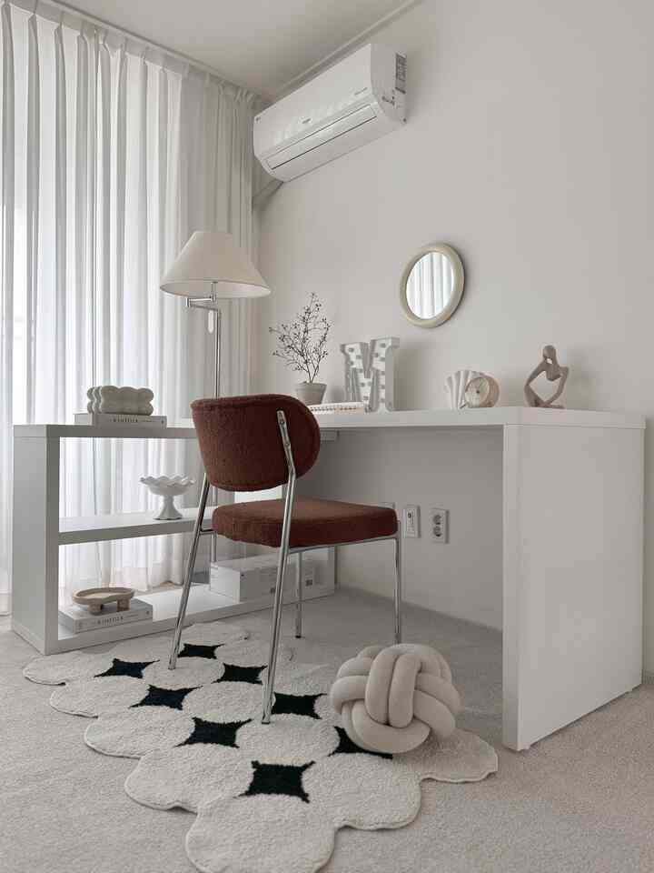 ホワイトトーンの寝室にシンプルでモダンな白いデスクとブラウンの椅子が配置された清潔感のある空間