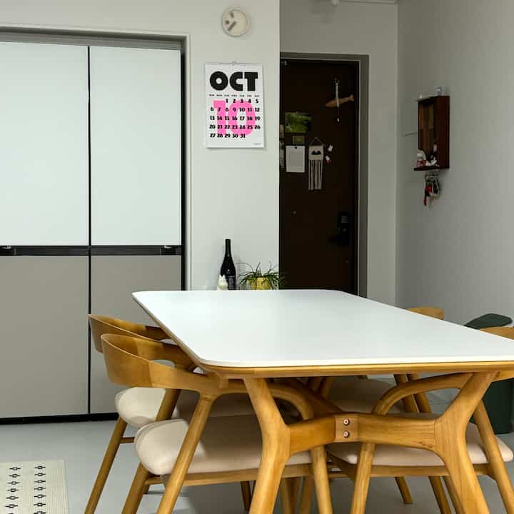 白と茶色のトーンのキッチン隣接のダイニング空間、木製のテーブルと椅子が中心に配置された清潔感のあるインテリア