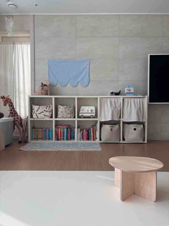 白と木目調が調和した子供部屋、青のストライプマットとおもちゃ収納が整った印象的な空間