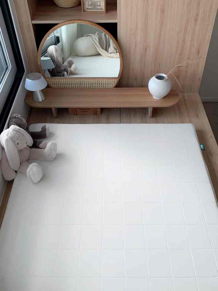 ナチュラルな色調の寝室、木製家具と白いマットレスが配置されたシンプルで居心地の良い空間