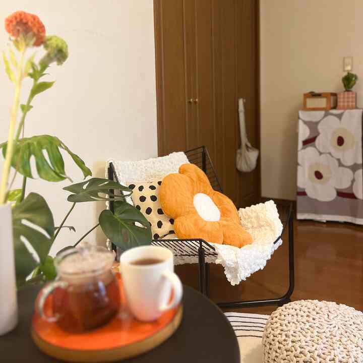 Natural wood tones and white walls define this living room, featuring floral cushions and a cozy blanket for comfort