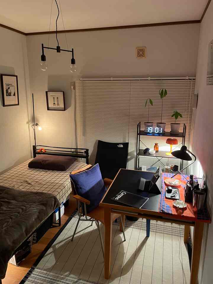 A cozy brown and black toned small bedroom with a desk and multiple indirect light sources creating a warm workspace