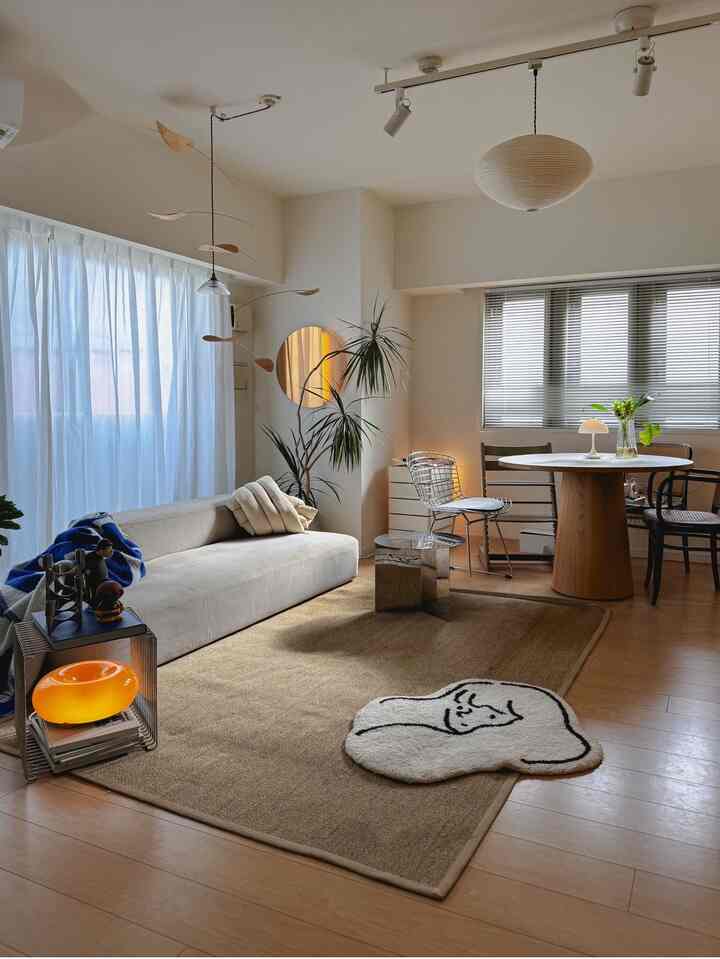 ベージュと白を基調としたリビング、中央に大きなラグとベージュのソファ、丸いダイニングテーブルが配置された温かみのあるナチュラルな印象のインテリア