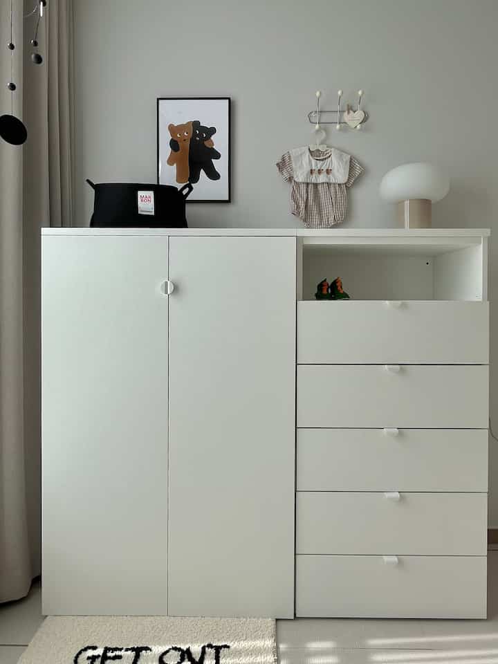 ナチュラルカラーとホワイトのトーンでまとめられた、赤ちゃんの服が配置された整頓された収納スペース