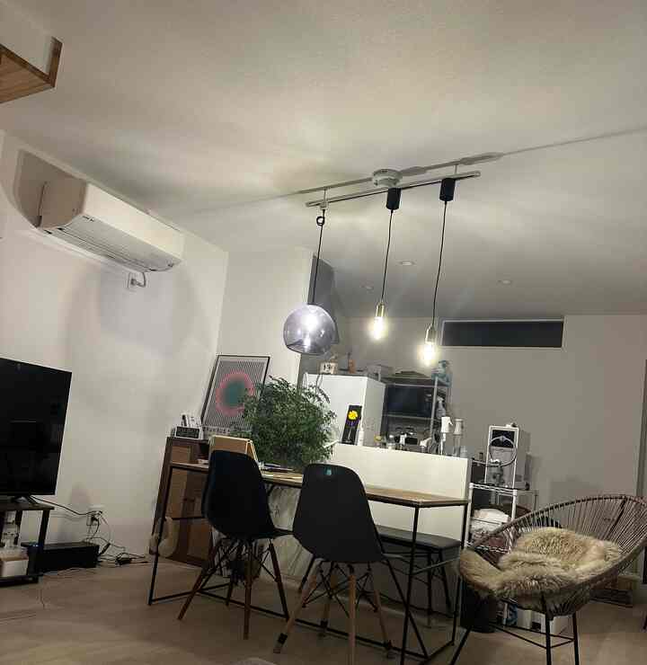 Modern kitchen-living space with white walls and black dining chairs, featuring pendant lights above dining table