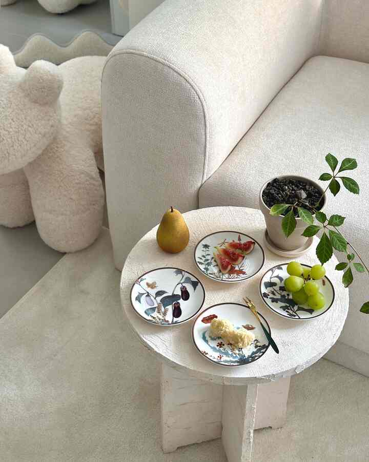 温かみのあるベージュ調のリビング、クリーム色のソファの隣に韓国陶磁器の皿とおやつが置かれた丸テーブルが配置されたナチュラルな雰囲気の空間