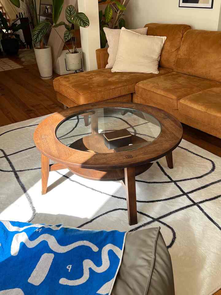 Natural color and wood tone living room featuring a brown sofa, round coffee table, and patterned carpet creating a cozy atmosphere