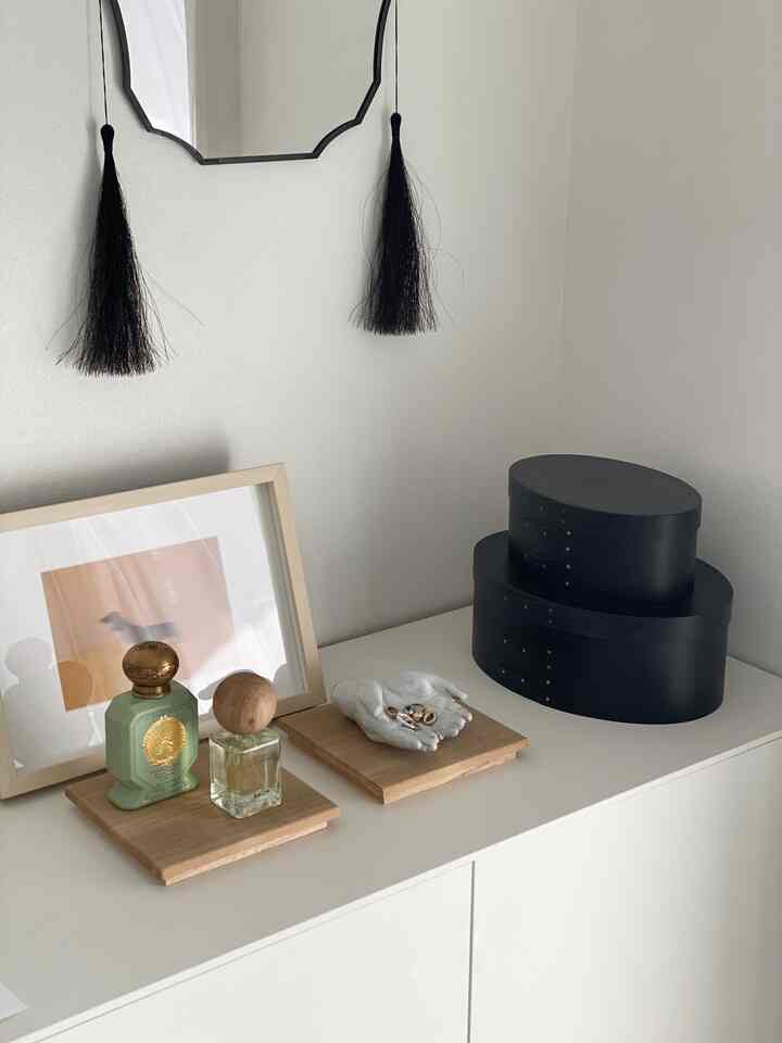 Minimal interior in white and wood tones featuring fragrance and accessories neatly displayed on trays