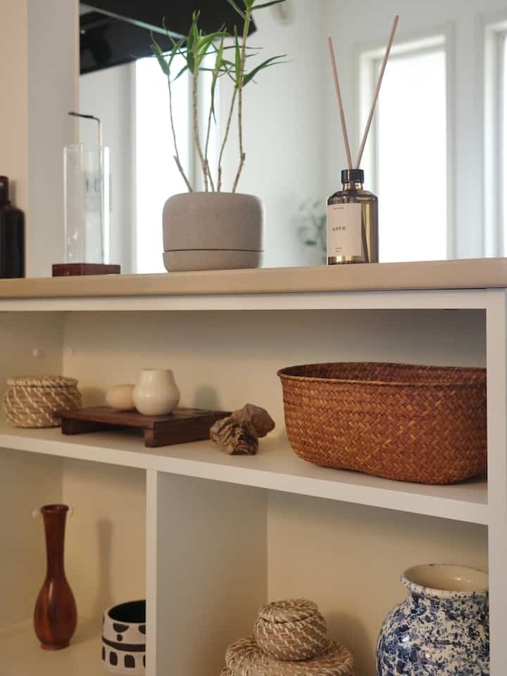 ナチュラルカラーとホワイトのキッチン棚、植物やバスケットなど自然素材の小物が配置された雰囲気のあるインテリア
