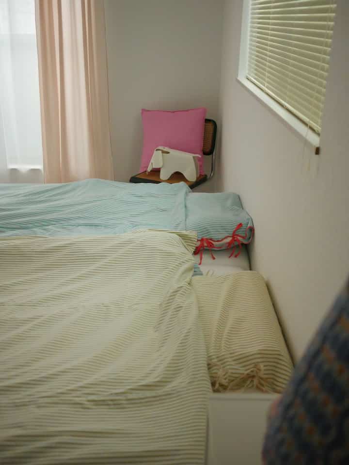 Natural color toned compact bedroom featuring striped bedding and a pink pillow on a chair