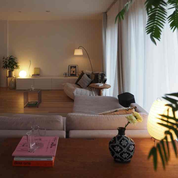 温かみのある木目調とナチュラルな雰囲気のモダンジャパンディリビング、ベージュのソファとフロアランプが配置された印象的な空間