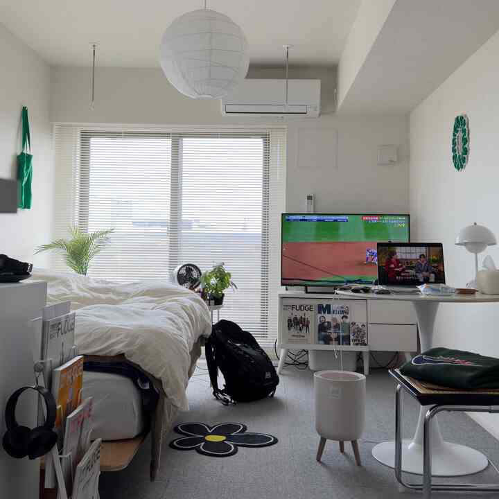 白を基調とした寝室、ベッドとテレビ台、植物が配置された雰囲気のあるインテリア