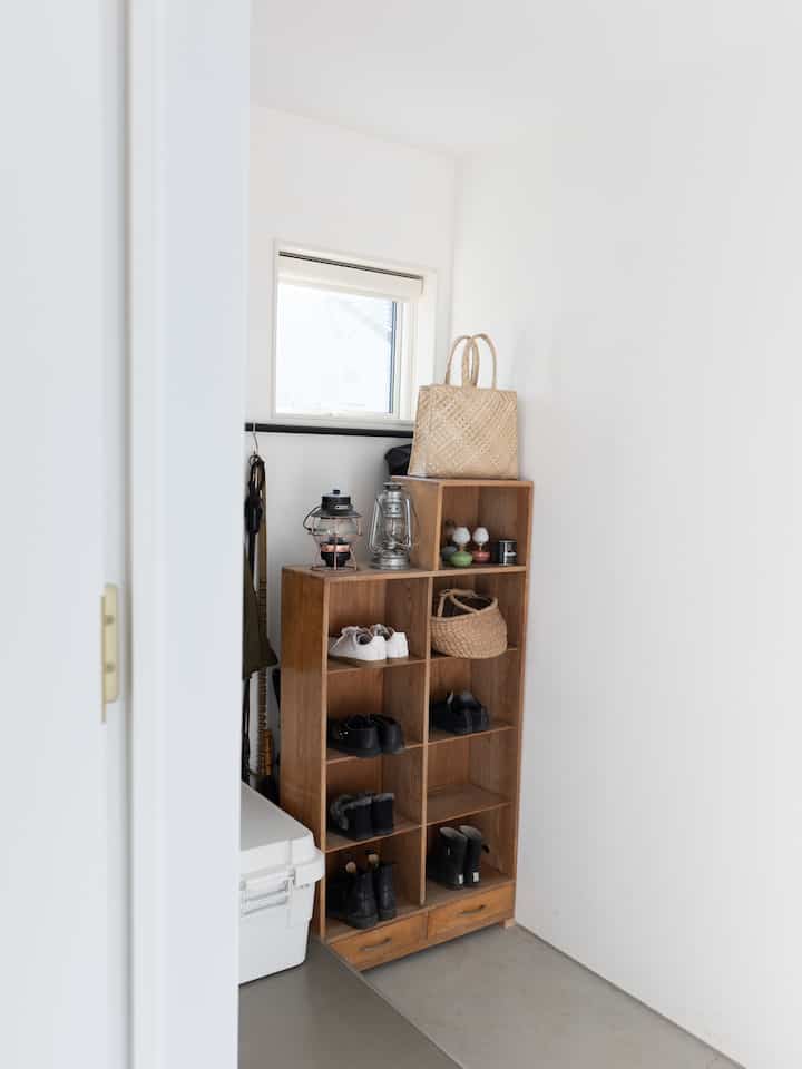 白い壁と茶色の木製シューズラックが配置された狭い玄関の雰囲気あるインテリア