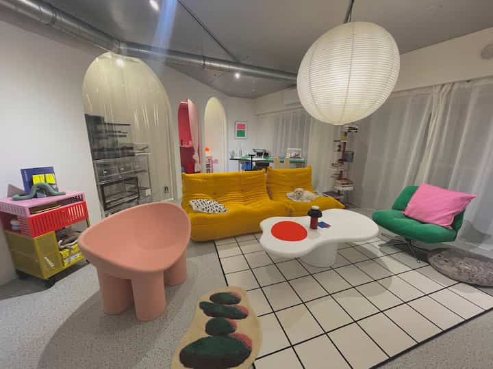 Colorful living room featuring a yellow sofa, pink chair, and artistic coffee table with a cozy atmosphere