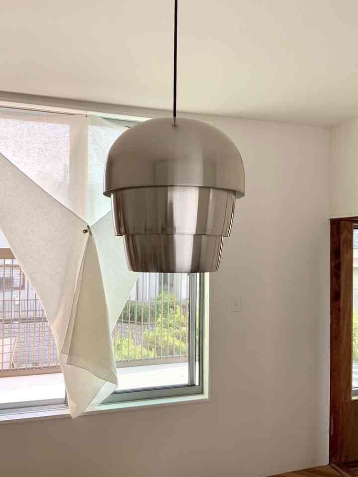 白とシルバーのトーンのリビング、中央にシルバーペンダントライトが配置されたシンプルなインテリア