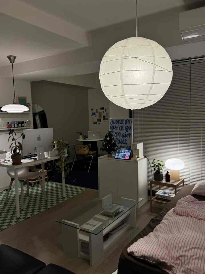 White and brown toned studio apartment featuring bed, desk, and lighting creating a cozy night atmosphere