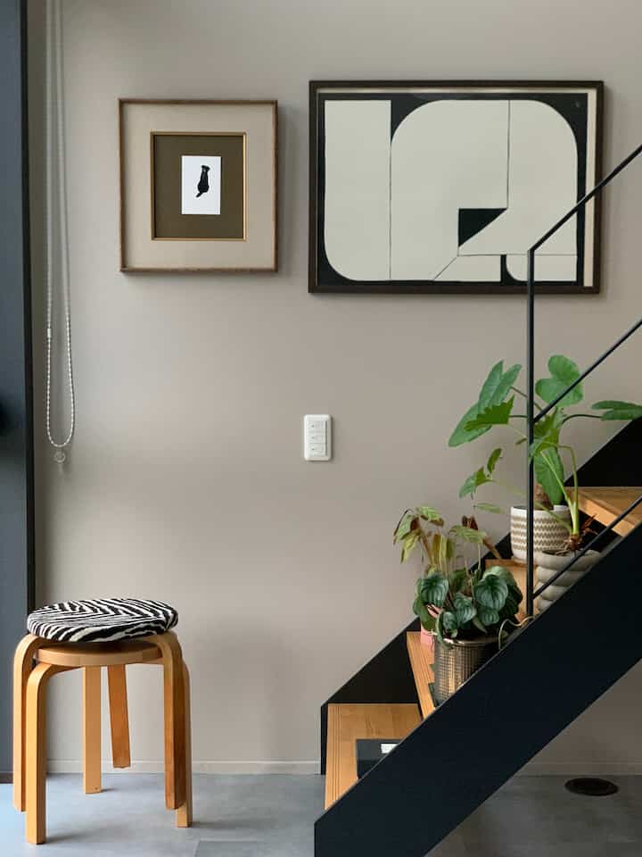 Soft beige wall and wooden stairs with plants in a Nordic style entrance space featuring a wooden stool