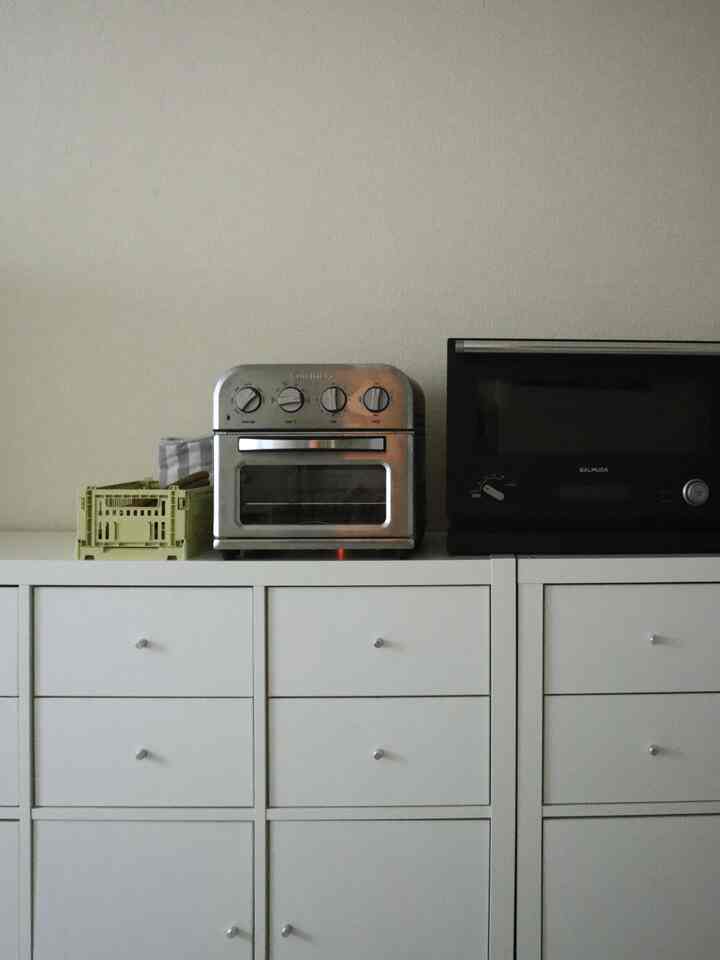 A white and gray toned kitchen featuring IKEA KALLAX cabinet topped with kitchen appliances and a container box in a clean inorganic interior style