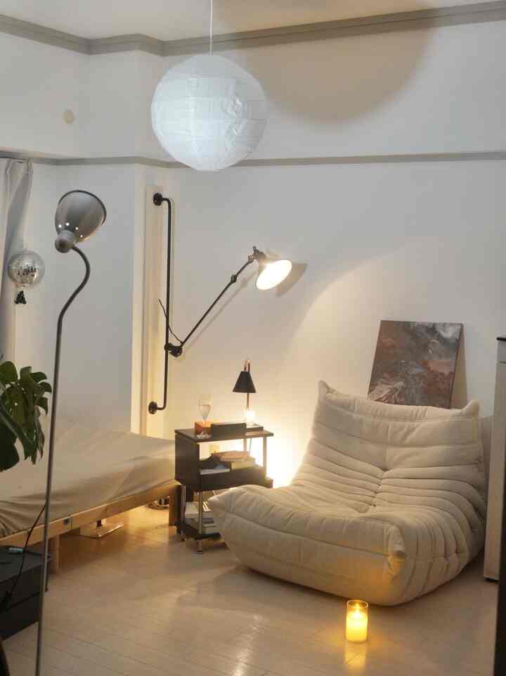White and wood tone small living room featuring a comfy mid-century modern lounge chair and a pendant light with warm ambiance