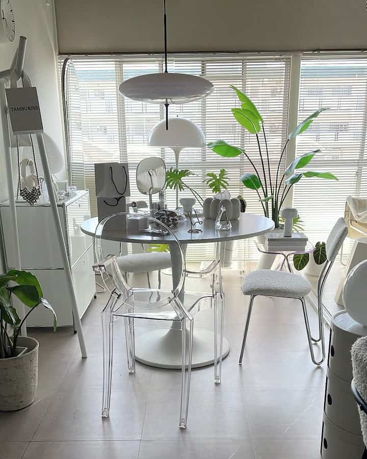 白と透明素材が調和したダイニング、ラウンドテーブルとモダンな椅子が配置された印象的な空間