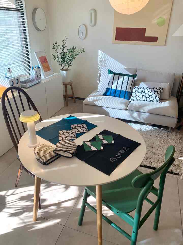 Bright and cozy living room in white and green tones featuring cushions and a round dining table