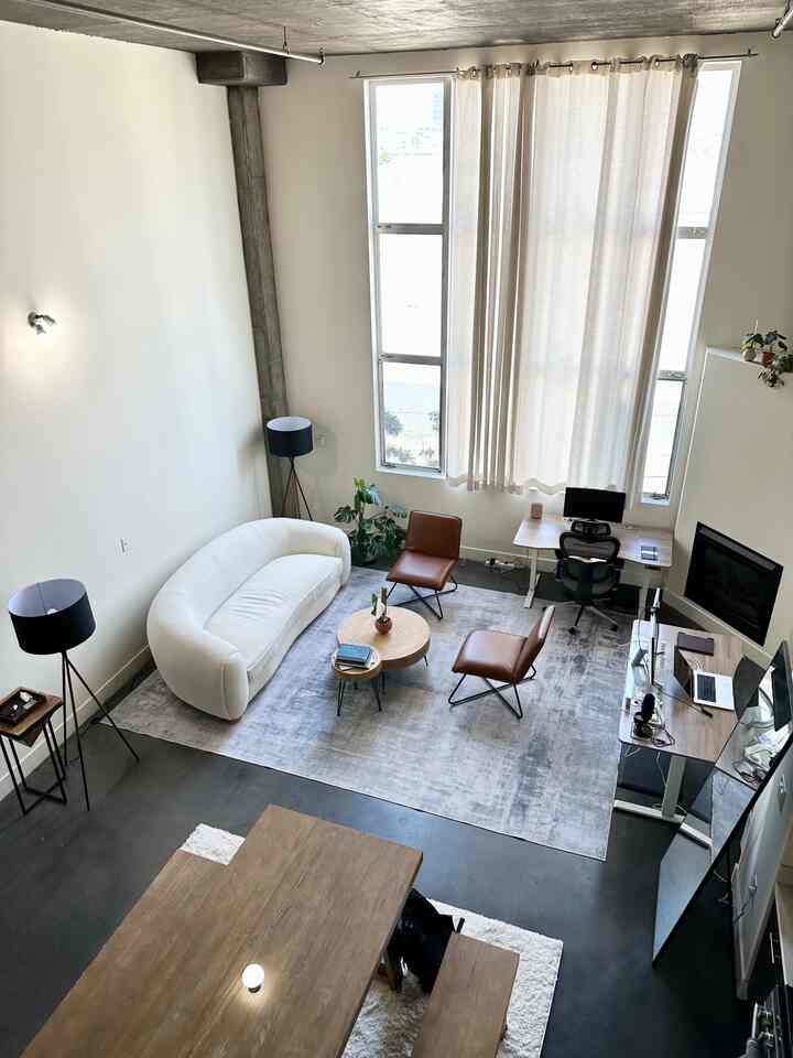 Natural modern living room with white and brown tones featuring cozy seating and a home office setup