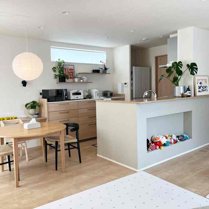 ナチュラルな色調のキッチンとダイニング、木製のダイニングテーブルと椅子が配置された明るく温かみのあるインテリア