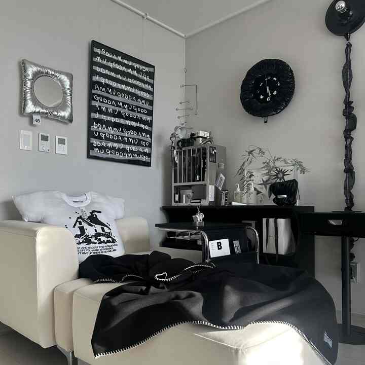 モダンなリビング、白いソファと黒のデスクが配置され、黒い額縁のアートと時計がアクセントになった洗練された空間