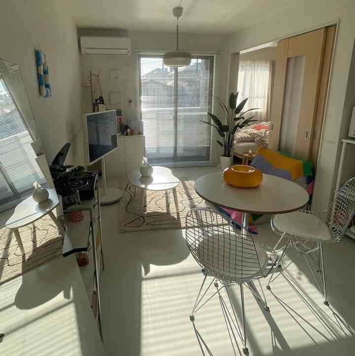 明るく白を基調とした1LDKのリビングと寝室、丸テーブルとソファ、キャットタワーが配置されたシンプルでモダンな印象的な空間