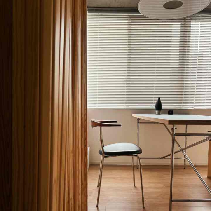 木目調の壁とクロムフレームのダイニングテーブルと椅子が配置されたモダンな1LDKのダイニングスペース