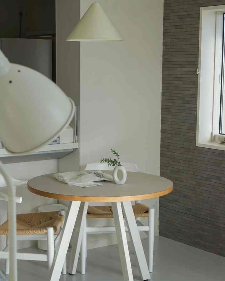 白とナチュラルカラーのダイニング、ラウンドテーブルとペンダントライトが配されたシンプルで落ち着いたインテリア