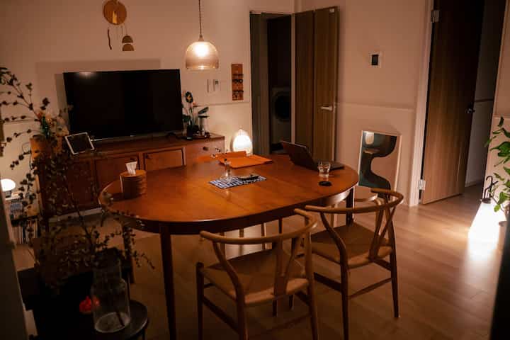 木目調のリビング・ダイニングルーム、ペンダントライトのあるラウンドテーブルが配置された暖かい空間