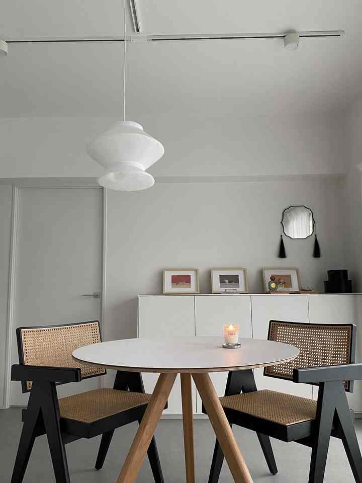 White and natural color toned dining room featuring a round table and cane dining chairs in a simple modern style