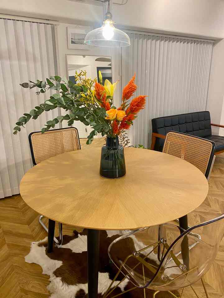 Wood tone and black accented dining room featuring a round central dining table with a flower vase creating cozy atmosphere