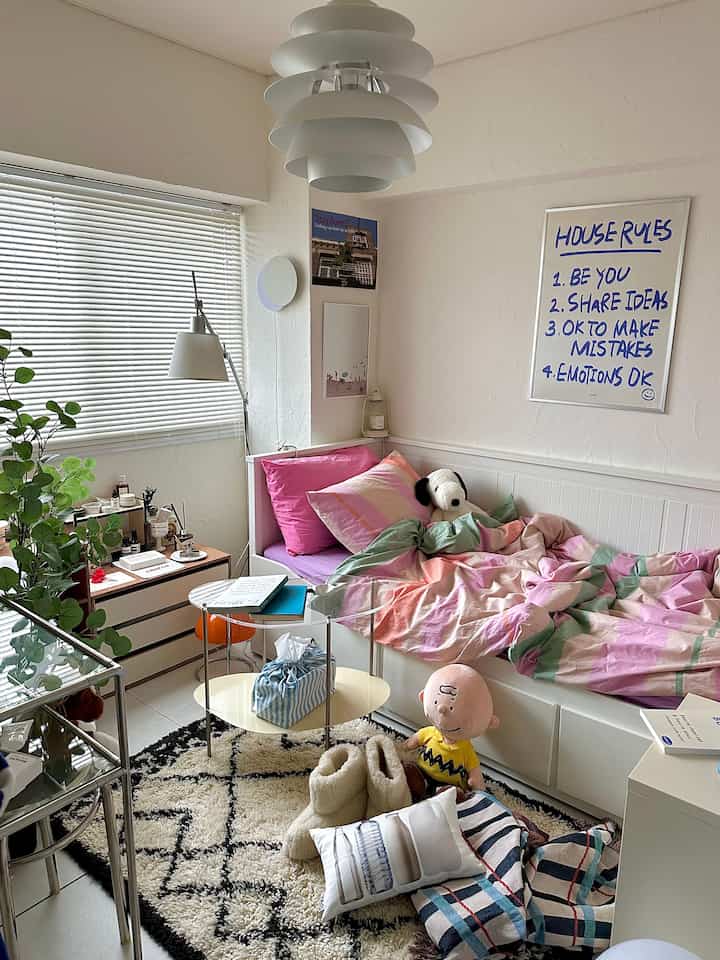 White and natural toned bedroom featuring white HEMNES daybed with pastel blanket, rug, and standing lamp creating cozy atmosphere