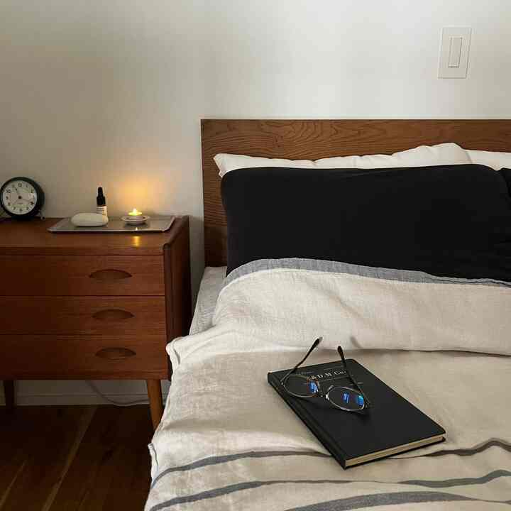 White-walled bedroom featuring a brown wooden bed and vintage chest of drawers in a simple Nordic style