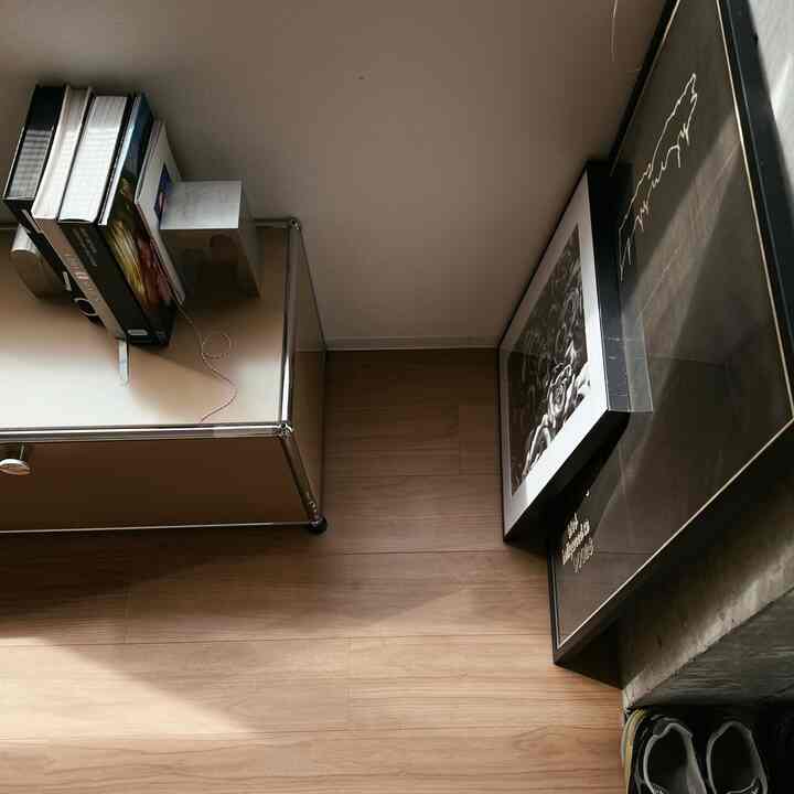 暖かみのあるベージュと木目調の1LDKリビング、ベージュのUSMサイドボードと床に立てかけられたポスターが配置された、柔らかく居心地の良い空間