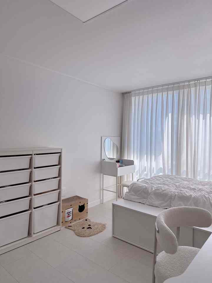 白を基調としたミニマルな寝室、収納キャビネットと猫のスペースが配置された、清潔感ある明るいインテリア