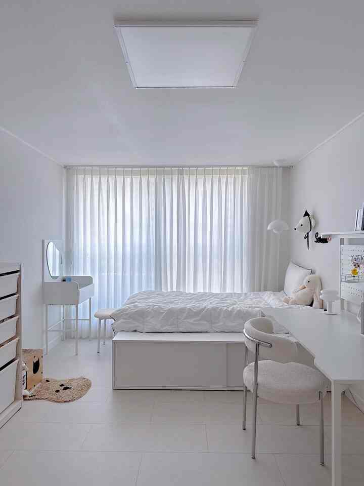 明るく白を基調とした子供部屋、収納付きベッドと小さな化粧台、デスクが配置されたミニマルな空間