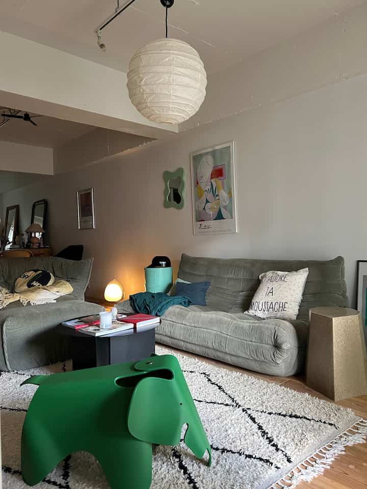 Natural color vintage living room featuring corduroy sofas and a green elephant stool in a cozy setting