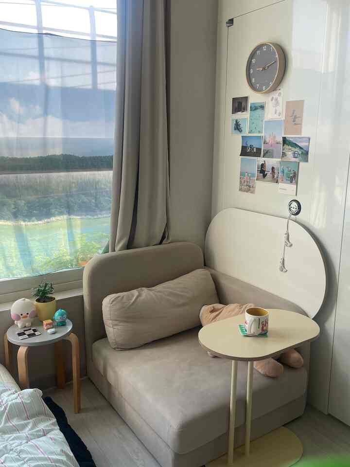 ベージュトーンのワンルーム、ソファベッドと折りたたみテーブルが配置された落ち着いたリラックス空間