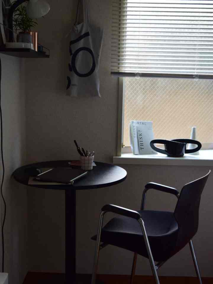 Small home office in black and silver tones, featuring a round table and chair by the window, creating a calm winter light ambiance