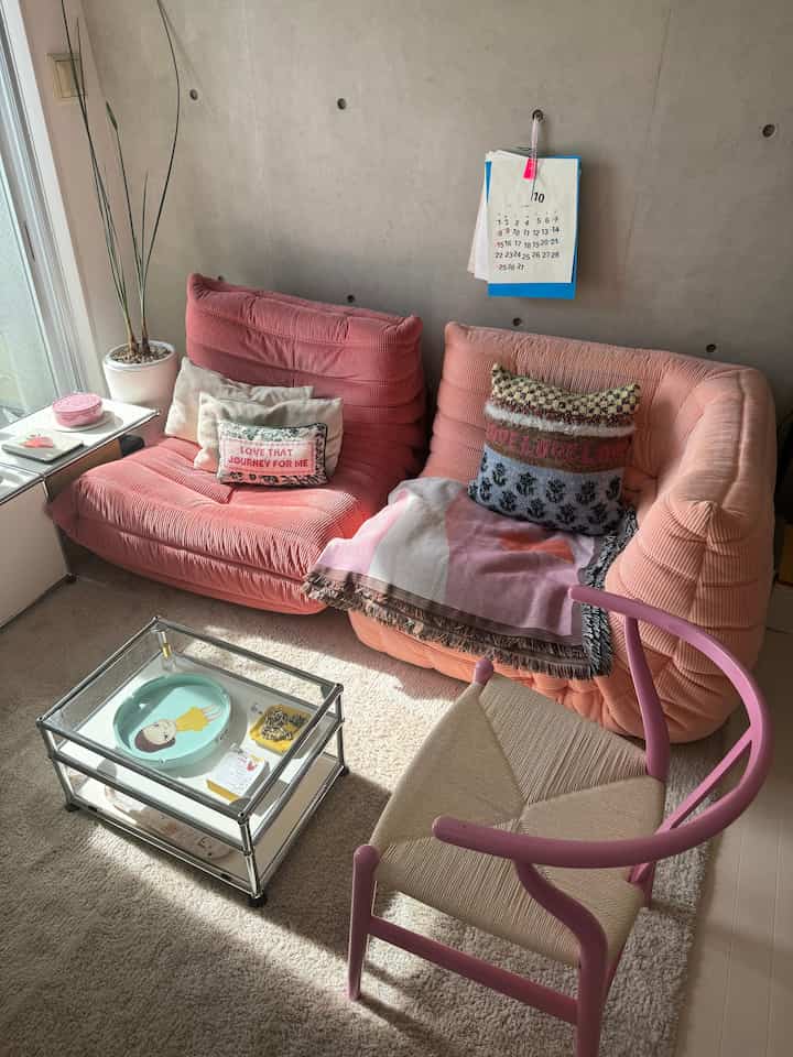 ピンク色調のリビング、ロゼトーゴのソファとYチェアが配置された、居心地よく暖かみのあるインテリア