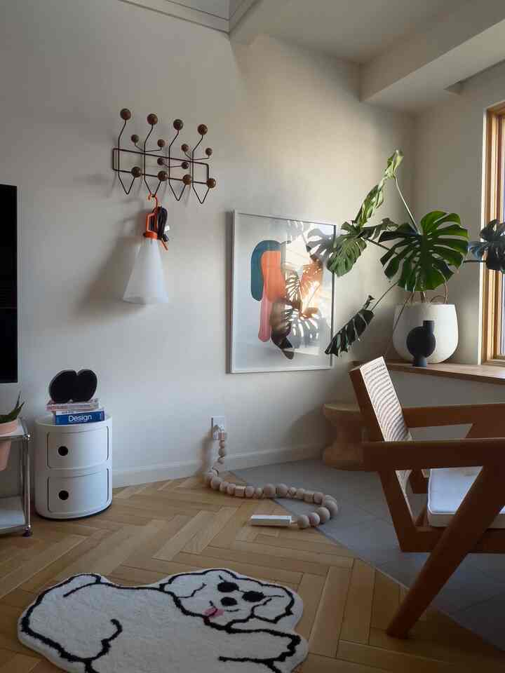 ナチュラルな木目調と白の調和の取れたリビング、モダンなラタンチェアと額装されたアートが配置された雰囲気のある空間