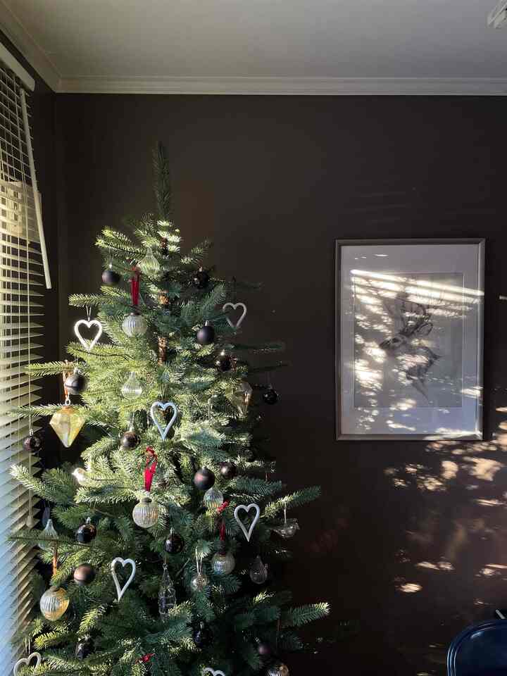 ブラウンの壁を背景にしたリビング、シルバーのクリスマスツリーと額縁が調和した雰囲気のあるインテリア