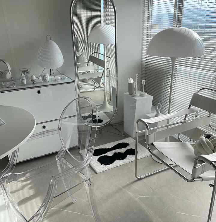 Modern living room in white and silver tones featuring transparent chair, full-length mirror and simple lighting for a clean atmosphere