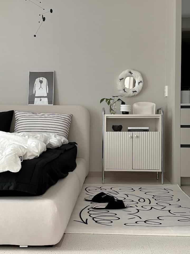 白と黒のモノトーンの寝室、グラフィティ柄のラグとモダンな家具が配置された清潔感のあるインテリア