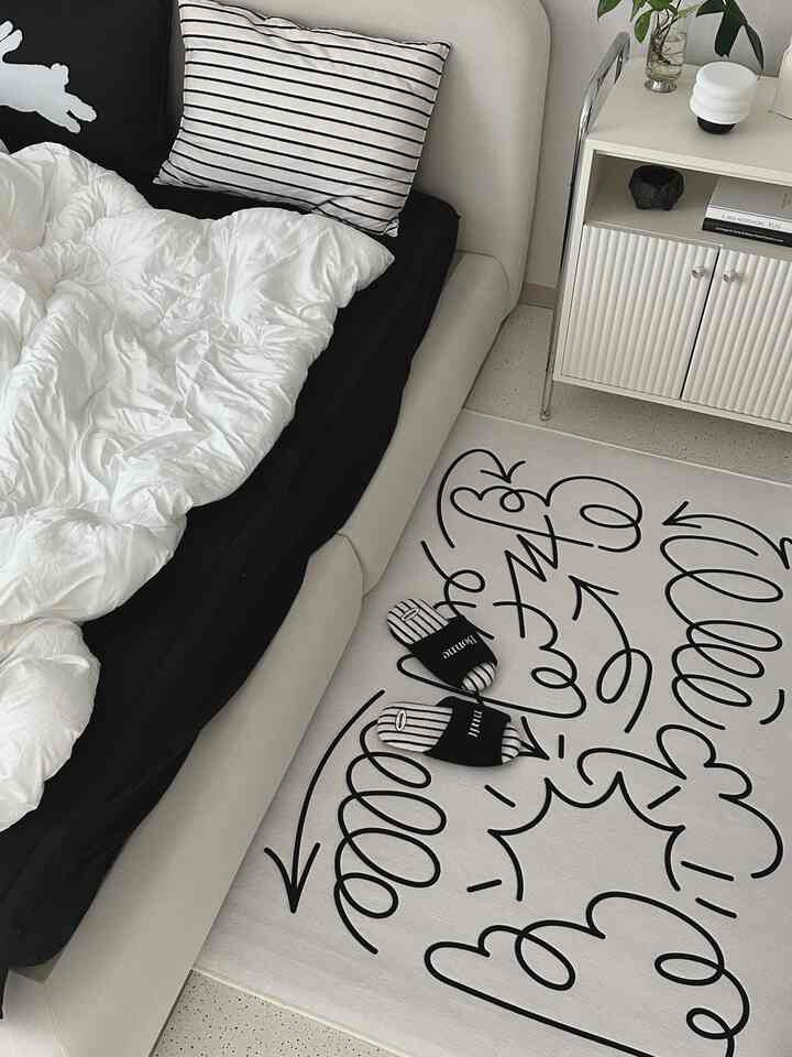 白とベージュの寝室、シンプルなベッドとラグが配置されたモダンな印象の空間