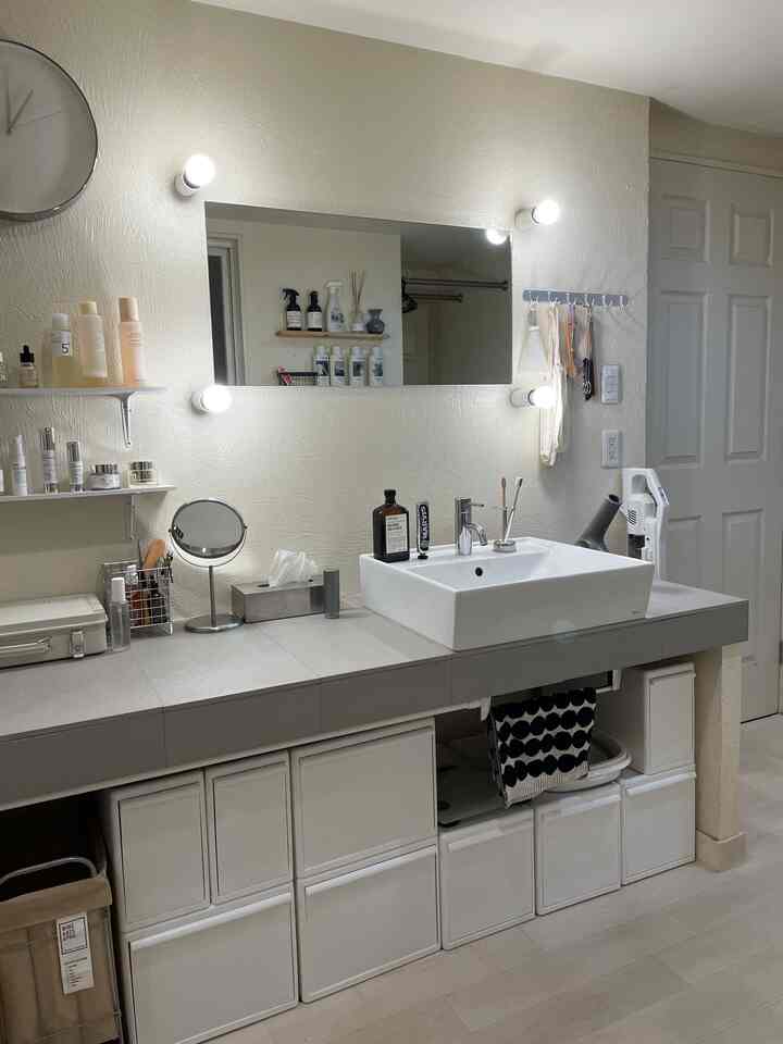 White and gray toned bathroom washbasin featuring simple storage cases, lighting, and a clean minimalist interior